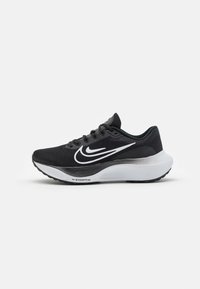 Zapatilla deportiva negra con parte superior de malla texturizada, swoosh blanco de Nike y una entresuela blanca en contraste. Presenta un diseño de cordones y suela de goma.