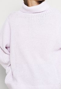 Vaaleanliila, ylivertainen neulottu villapaita korkealla resorikauluksella ja väljillä hihoilla, jossa on teksturoitu, avoin neulekuvio.