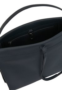 Tmavě modrá kožená taška přes rameno s strukturovaným tvarem, otevřeným horním okrajem, vnitřní kapsou na zip a dvojitými uchy. Texturovaný povrch.