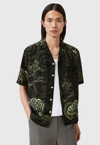 Short-sleeved black shirt with green dragon and swirl pattern, button-down front, lightweight fabric, worn over a white T-shirt.