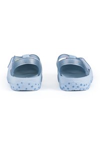 Blaue Sandalen mit einer strukturierten Sohle, die kleine Sternmuster aufweist. Das Obermaterial ist semi-transparent mit Glitzerakzenten und verstellbaren Riemen.