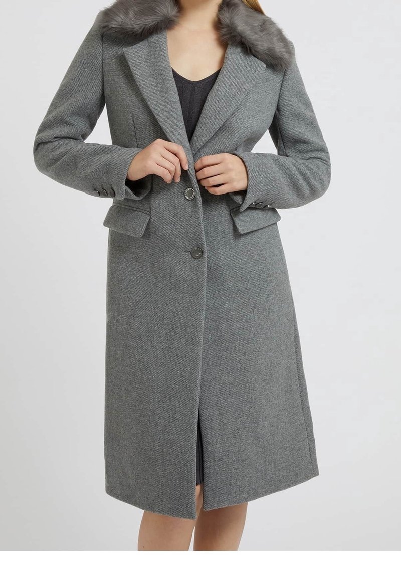 Abrigo de mezcla de lana gris con cuello de piel sintética, diseño de un solo botón y dos bolsillos frontales. Presenta un corte a la altura de la rodilla y una abertura lateral.