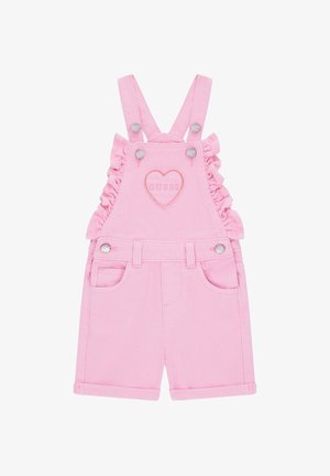 Salopette corta rosa per bambina con volant ai lati, bretelle regolabili, tasche frontali, bottoni metallici e toppa a forma di cuore con ricamo "GUESS".