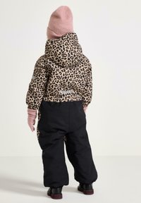Giacca puffer con stampa leopardata e una sezione inferiore nera, abbinata a un cappello e guanti in maglia rosa. Presenta un cappuccio e dettagli riflettenti.