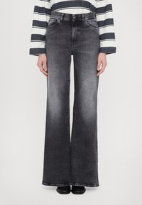 Jeans in denim nero a vita alta e gamba larga con una finitura sfumata, dotati di cinque tasche e chiusura con bottone. Tessuto texturizzato con una sensazione di morbidezza.