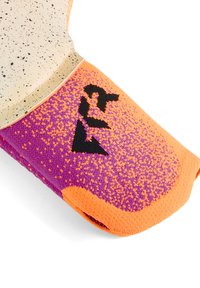 Zapato en colores beige, púrpura y naranja; tejido texturizado con motas; presenta un logo en negro; punta redondeada y un diseño acolchado.