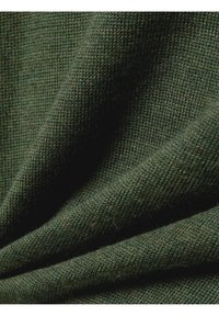 Grüner, texturierter Stoff mit einem gestrickten Muster, das subtile Schattierungsvariationen und ein weiches, gemütliches Aussehen aufweist.