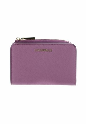 Portefeuille en cuir violet avec bords arrondis, fermeture éclair dorée et logo COCCINELLE centré sur le devant.