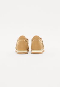 Tan semskodde sneakers med en polstret såle, med rund tå og teksturerte paneler. Naturlig farge og minimalistisk design.