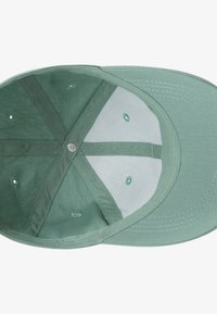 Zaļa auduma beisbola cepure ar plakanu malu, tai ir līdzenas iekšpuses un ventilācijas caurumi gaisa caurlaidībai.