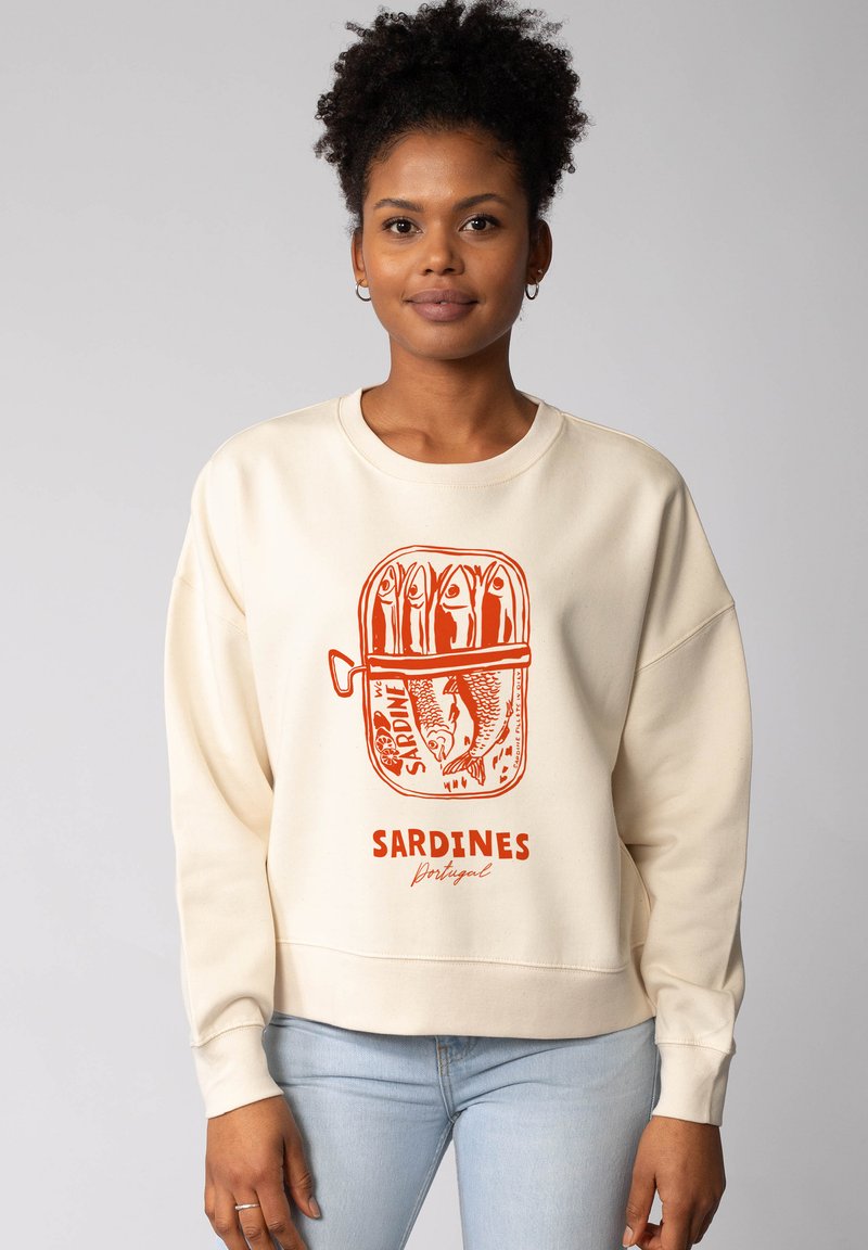 Cream-colored sweatshirt featuring an orange sardine tin graphic with fish illustrations and "SARDINES Portugal" text. Regular fit, ribbed cuffs.