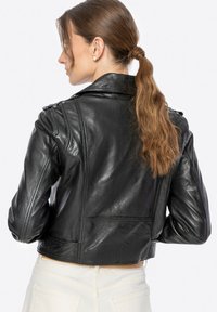 Schwarze Lederjacke mit tailliertem Schnitt, Schulterklappen, strukturierter Oberfläche und cropped Silhouette.
