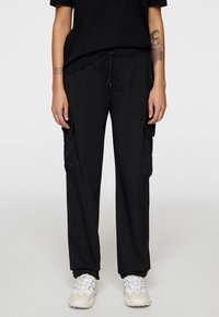 Czarne spodnie cargo o luźnym kroju, z elastycznym paskiem w talii i sznurkiem. Posiada boczne kieszenie i gładki, lekki materiał.
