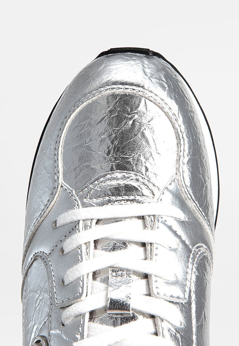 Basket en métal argenté avec une tige texturée, des lacets blancs et une semelle noire. Le bout arrondi et les accents cousus mettent en valeur le design.