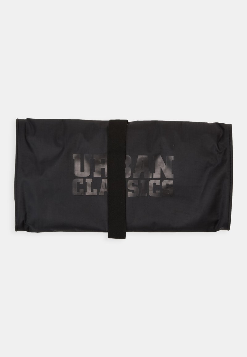 Borsa di stoffa nera con un design arrotolato, fissata con una tracolla nera. Sul davanti sono stampate le parole "URBAN CLASSICS" in un carattere bold e sbiadito.