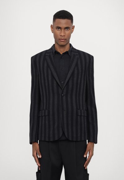 Černý a šedý pruhovaný blazer s upraveným designem, s dvěma předními kapsami a zapínáním na jeden knoflík. Texturovaná látka.