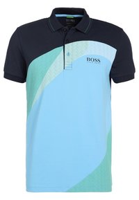 Pikétröja i ljusblått och marinblått med diagonalt grönt mönster, korta ärmar, krage, treknappslås och logotyp på bröstet.