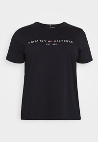 Camiseta negra de manga corta con el texto "TOMMY HILFIGER EST. 1985" y un pequeño logo rojo, blanco y azul centrado en el pecho.