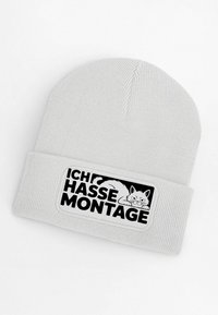 Gray knit beanie with a ribbed texture features a prominent patch displaying a cat graphic and the text "ICH HASSE MONTAGE" in black.