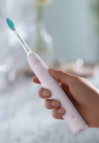 Spazzolino elettrico Philips Sonicare, con un corpo ergonomico rosa chiaro, una testina bianca con setole verdi e blu, e un pulsante di accensione.