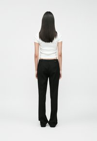 Īsām piedurknēm baltas augstās blūzes, kas saderē ar melnām biksēm ar augstu jostasvietu, kurām ir gluda faktūra un minimālisma dizains.