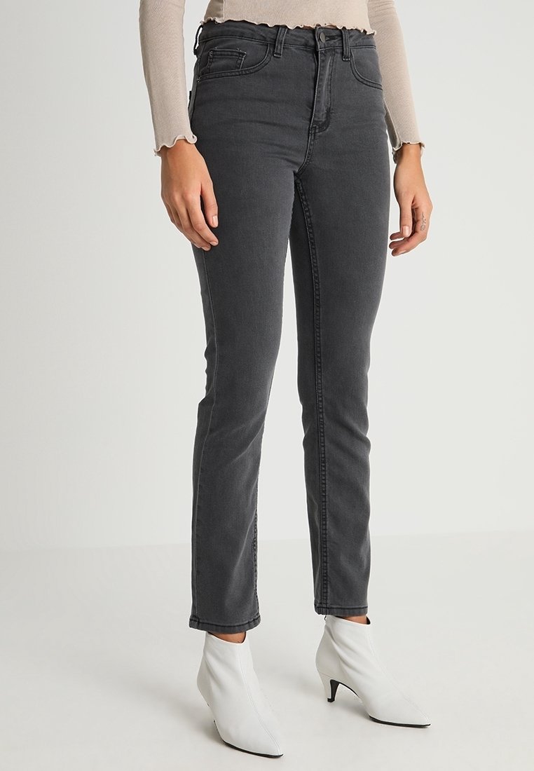 Jeans negros de cintura alta con un ajuste slim y cinco bolsillos, que cuentan con un zipper frontal y un sutil desgastado.