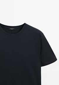 Marineblå kortærmet T-shirt lavet af blød bomuld med rund halsudskæring og et mærke på nakken bagtil. Glat tekstur.