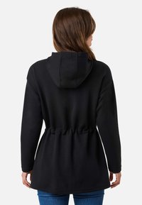 Schwarzer Kapuzenpullover mit gerafftem Bund, langen Ärmeln und einer glatten Textur. Verfügt über einen lässigen Schnitt und ein einfaches Design.