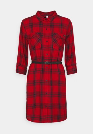 Punamusta ruudullinen pitkähihaiskotimekko, jossa edessä napit, kaksi rintataskua, käännetyt hihansuut ja kapea musta vyö vyötäröllä.