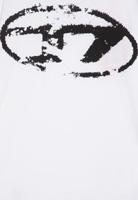 Hvit bomulls t-skjorte med et stort, abstrakt svart grafisk design med en slitt tekstur. Korte ermer og rund hals.