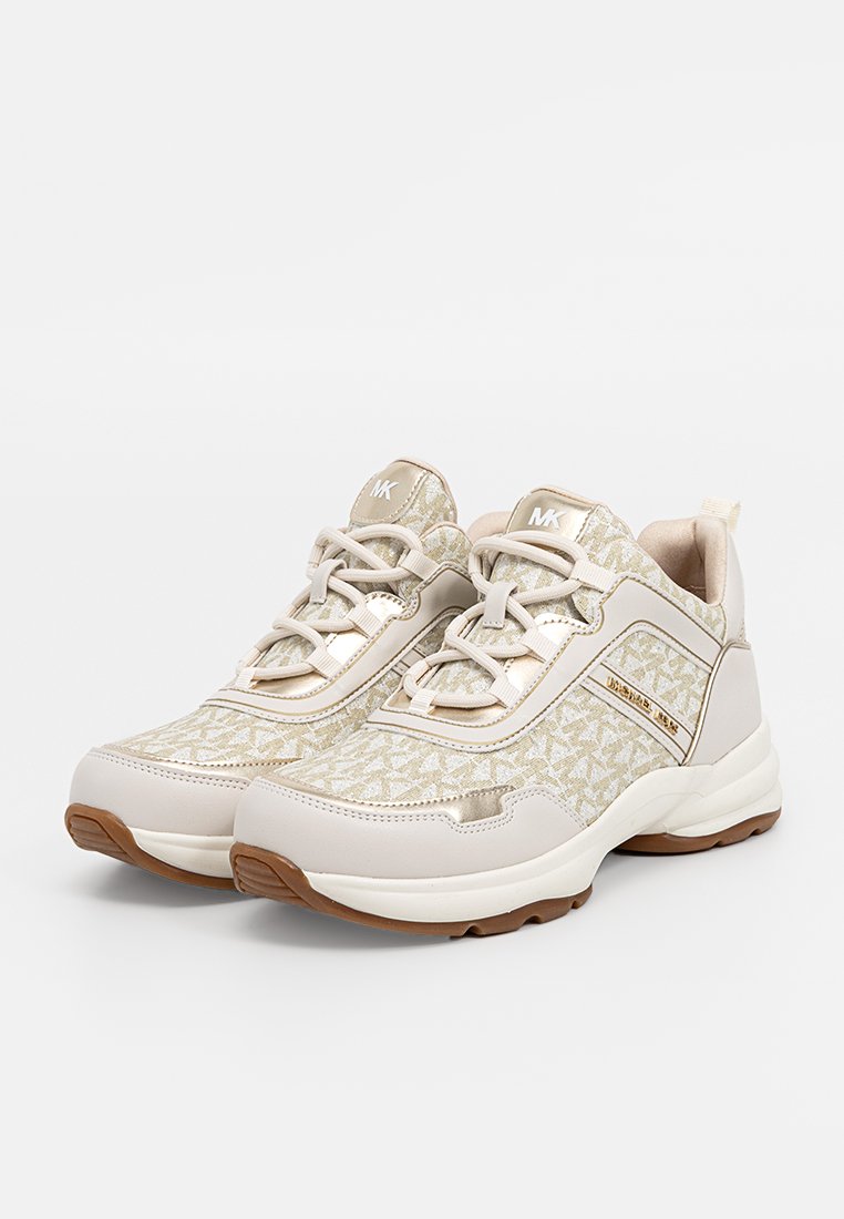 Baskets Michael Kors beige et blanches avec un tissu à motifs, des lacets blancs, des accents dorés et des semelles en caoutchouc marron, présentées côte à côte.