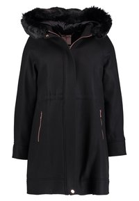 Cappotto invernale nero con cappuccio foderato in pelliccia sintetica nera, cerniera frontale nascosta da una patta e tasche laterali con zip.
