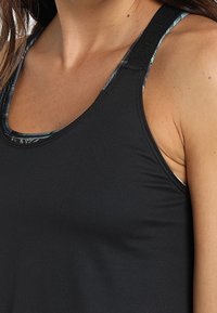 Débardeur de sport noir avec un col en scoop et des bretelles étroites, présentant une doublure colorée à motifs visible sur les bords. Tissu doux et extensible.