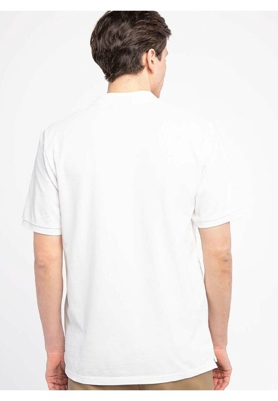 Homme aux cheveux courts et foncés portant une chemise blanche unie à manches courtes, debout de dos sur fond blanc.