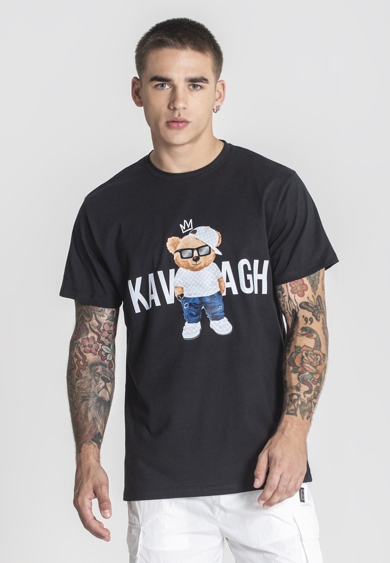 Černé bavlněné tričko s grafickým potiskem karikatury medvěda, který nosí sluneční brýle a klobouk, s nápisem "KAVAGH" v tučném bílém písmu pod ním.