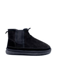 Bottines en daim noir avec panneaux élastiques sur les côtés et une semelle en caoutchouc texturée. Présentent une finition lisse et des accents de couture minimale.