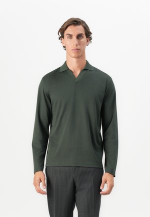 Cămașă polo cu mânecă lungă de culoare verde închis, cu guler în formă de V și guler ribat, realizată dintr-un material neted. Pur exercitată cu pantaloni cu dungi fine.