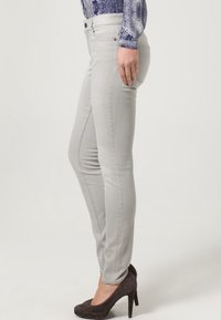 Ljusgrå smala jeans med femfickorsdesign, som har en figurnära silhuett, diskret textur och standard metallelement.