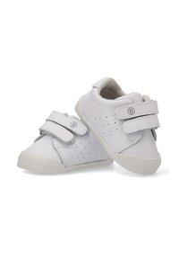 Zapatos de piel blanca con detalles perforados, tiras de velcro, puntera redondeada y una suela de goma texturizada. Con detalles en gris.