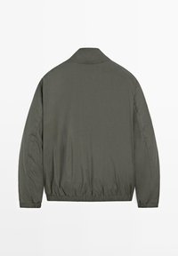 Giacca leggera verde oliva con maniche lunghe, polsini ed orlo elasticizzati, vista da dietro su sfondo bianco.