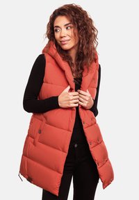 Rote gepolsterte Weste mit Kapuze, ausgestattet mit einem gesteppten Design, vorderen Druckknöpfen und seitlichen Taschen. Über einem schwarzen langärmligen Oberteil getragen.