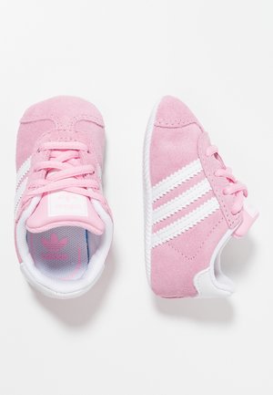 Rosa Wildleder-Kleinkind-Sneaker mit weißen Streifen, Schnürsenkeln und weichen Sohlen, dargestellt aus der Vogelperspektive und seitlicher Ansicht auf weißem Hintergrund.