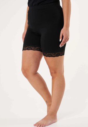 Shorts noirs en stretch avec une bordure en dentelle à l'ourlet, présentant une texture lisse et une coupe ajustée s'étendant jusqu'au milieu de la cuisse.