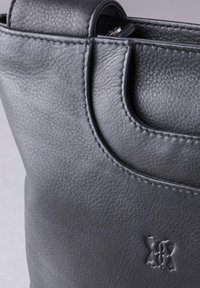 Black leather tote bag with smooth texture, rounded handles, and subtle embossed logo. Features neat stitching along edges.