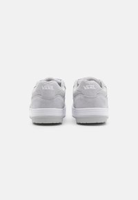 Grå semsket skinn og lær sneakers med hvite såler. Bakfra vises "VANS" logoen på hælen. Minimalistisk design med avrundet form og polstring.