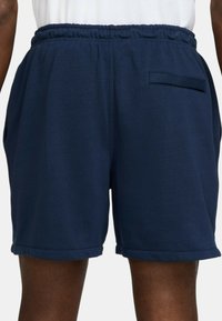Shorts en coton bleu marine avec une taille élastique, deux poches latérales et une petite poche arrière, présentant une texture unie et un ourlet replié.