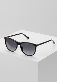 Ochelari de soare negri cu lentile degradé, formă pătrată, ramă din plastic lucios și accente metalice pe brațe.