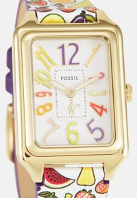 Montre rectangulaire Fossil dorée avec des chiffres colorés et un bracelet blanc décoré de diverses illustrations de fruits.