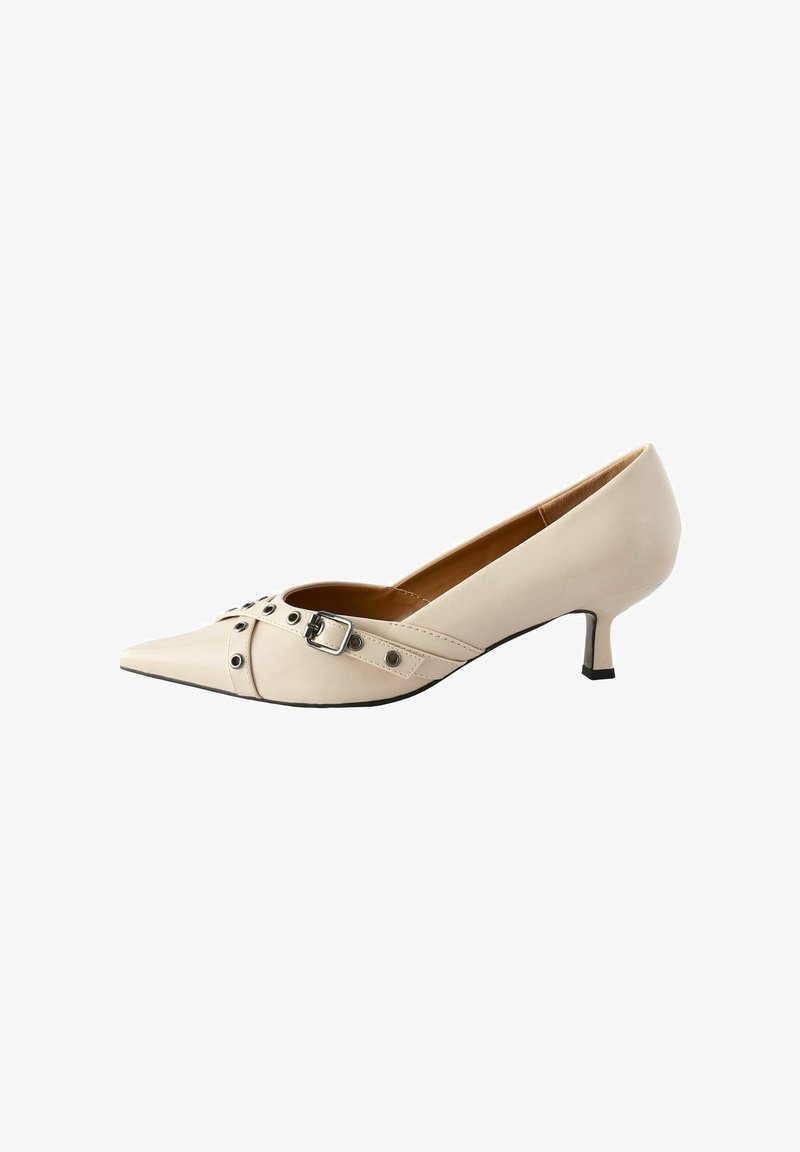 Chaussure à talons hauts en cuir beige avec un design à bout pointu, comportant une boucles et des clous sur la tige ainsi qu'un petit talon de type kitten.