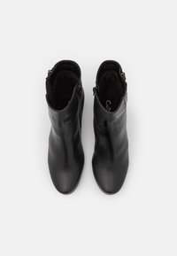 Botines negros de cuero liso, con una silueta elegante, cremallera lateral y un forro interior suave.